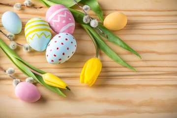 Colorful Easter eggs with yellow Tulip hand painted on a light wooden background. Festive spring card
