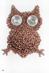 Owl made of roasted coffee beans isolated on white wooden background