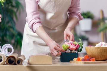 Image of florist woman in apron with marshmallow, marmalade at table