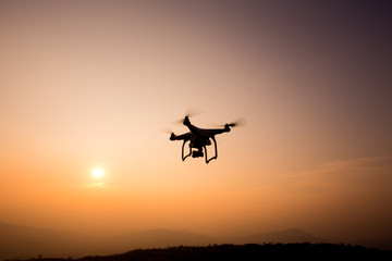 Fototapeta na wymiar Drone silhouette flying in sunset landscape. 