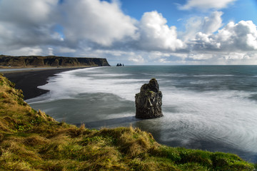 view to the black beach of Dyrholaey in Iceland with a single rock in the front, taken with time...