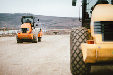 Vibratory Soil Compactor during road and highway construction. Industrial roadworks with heavy-duty machinery