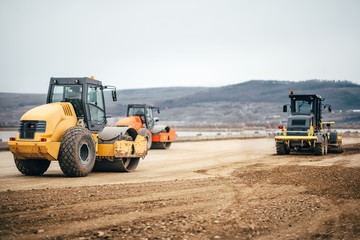 Vibratory Soil Compactors on highway construction site. Industrial roadworks with heavy-duty machinery