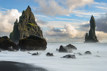 the black beach of Reynisfjara in Iceland with giant rocks and a dangerous breakwater, taken with time exposure.