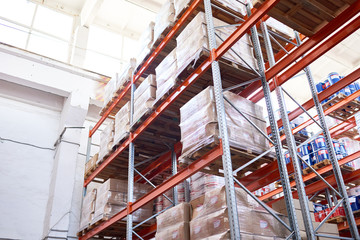 Low angle view at tall storage shelves with packed goods in warehouse, background with copy space