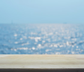 Empty wooden table with blur blue sea waves with bokeh light, for your product display