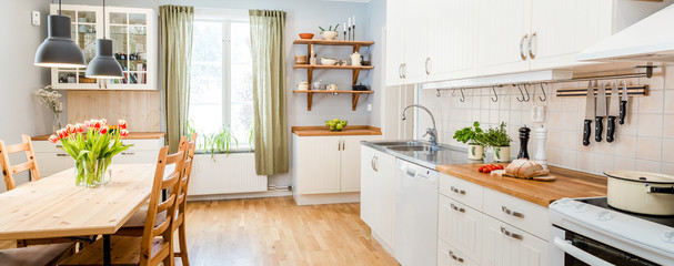 banner of a kitchen with kitchen table  and breakfast at the kitchen counter top white cupboards and wooden floor - obrazy, fototapety, plakaty