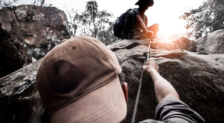 Hiking male help each other in mountains with sunlight.