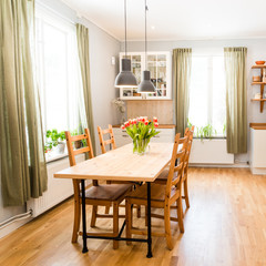 kitchen table with bunch of orange tulips and green curatains by the window