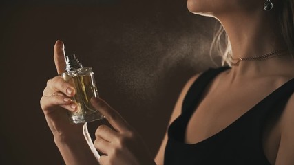 Sensual girl spraying fragrance in slow motion, with scent particles. Concept of sensual feminine scent.