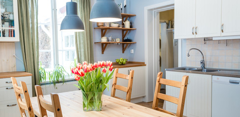 kitchen interior with green curtains by the window tulips on the kitchen table