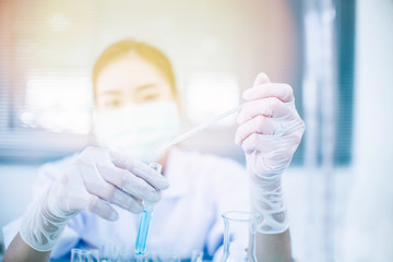 Asian women scientist with test tube making research in clinical laboratory.Science, chemistry, technology, biology and people concept