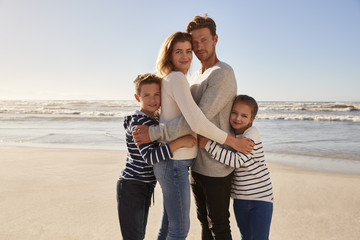 Portrait Of Loving Family Embracing On Winter Beach