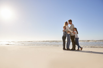 Loving Family Embracing On Winter Beach