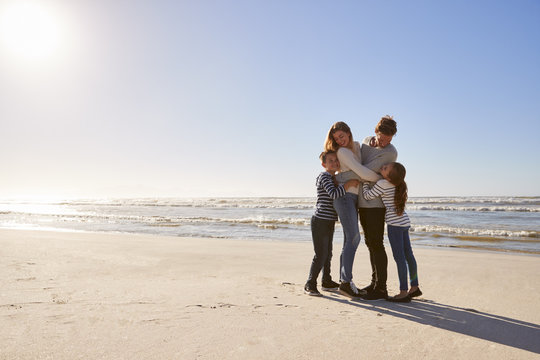 Loving Family Embracing On Winter Beach