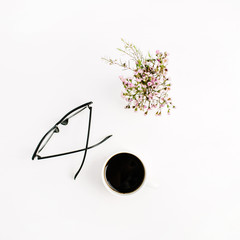 Minimal flat lay, top view composition with glasses, coffee cup and wildflowers on white background.