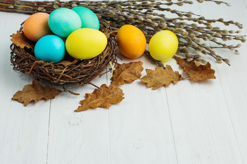 colored Easter eggs in the nest on a white table