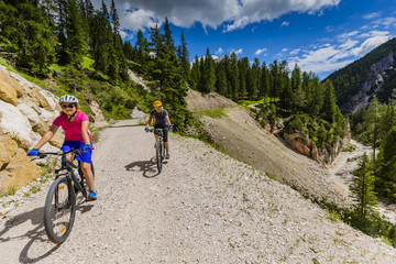 Naklejka premium Mountain biking woman and young girl along river in Dolomites, Italy