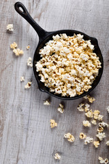  Prepared popcorn in frying pan, corn seeds in bowl and corncobs on kitchen table.Air salty popcorn. Salt popcorn on the wooden background . Chees .Popcorn texture