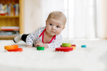 Cute baby girl playing with colorful wooden rattle toy