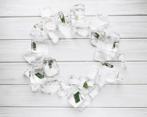Flat lay of ice cubes with frozen aloe inside on white wooden table