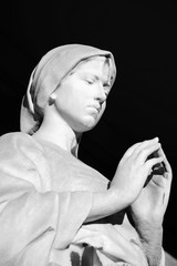Old statue of a woman praying inside the monumental cemetery of the Certosa di Bologna. The public cemetery was established in 1801.