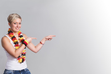 Lächelnder weiblicher Deutschlandfan zeigt mit den Fingern auf etwas hin