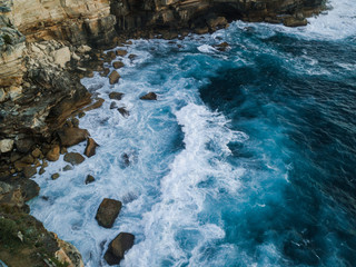 Wave breaking into coastal rock cliff.