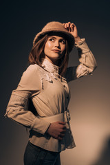 side view of pensive woman in stylish clothing and hat looking away