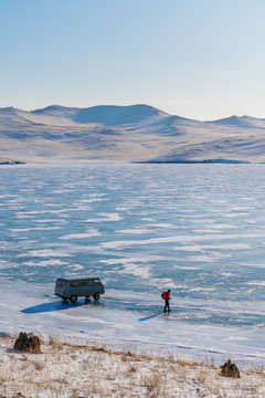 Travel destination in Siberia, Russia. a man with car on frozen lake Baikal in winter