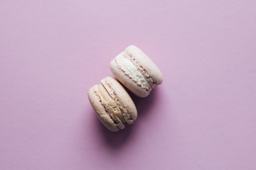 Composition of delicious macaroons on purple table, sweet dessert