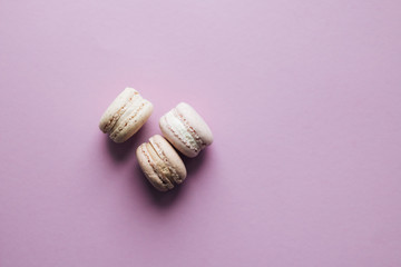 Composition of delicious macaroons on purple table, sweet dessert