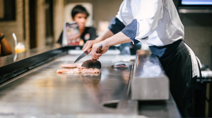 Hand of man take cooking of meat with vegetable grill, Chef cooking wagyu beef in Japanese teppanyaki restaurant