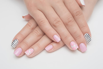 Manicure with rhinestones in the shape of hearts and pink balls on white and red nail Polish on a white background.