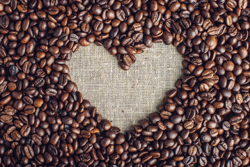 Textured background of coffee beans in heart-shaped top view. Concept love for a fresh and fragrant drink.