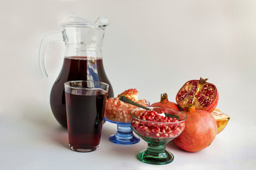 pomegranate grains and juices in glass bowls and glass pitcher on the white background.Close up taken,isolated. 
