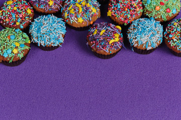 Fresh sweet cupcakes on a purple background.