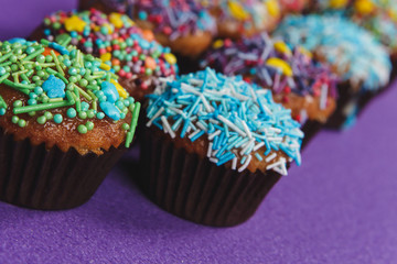 Fresh sweet cupcakes on a purple background.