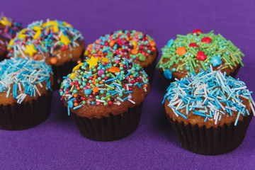Fresh sweet cupcakes on a purple background.