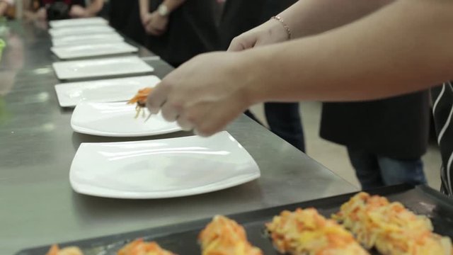 A cook teaches chefs to lay out products.