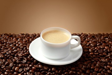 Cup of coffee surrounded by coffee beans