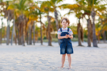 Naklejka premium Little kid boy having fun on tropical beach