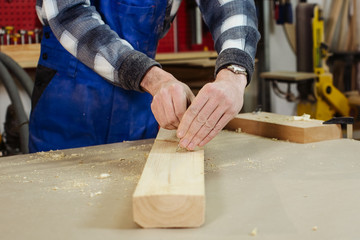 work with a bar on a wooden workbench. Hands of the worker, manipulation with measurements and...