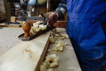 woodworker keeps in the hands of the plane,  stands on a timber bar and is ready for work