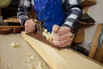 woodworker keeps in the hands of the plane,  removes chips from the wood and aligns the timber