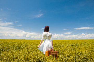 girl with suitcase at wheat field