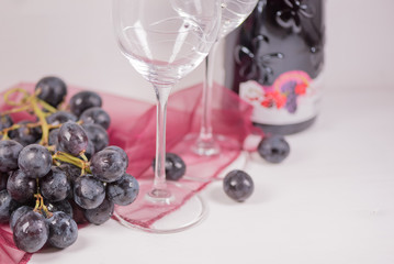 Fresh grape and red wine on the white table with two glasses, selective focus