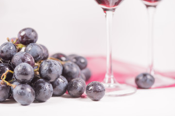 Fresh grape and red wine on the white table with two glasses, selective focus