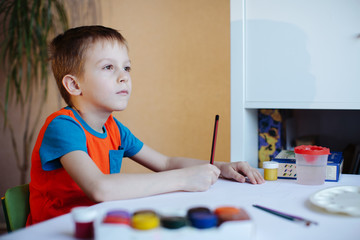 boy draws on paper with a pencil and bright colors.Boy draws in cartoon style. School, kindergarten.  Children design.