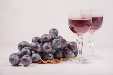 Fresh grape and red wine on the white table with two glasses, selective focus